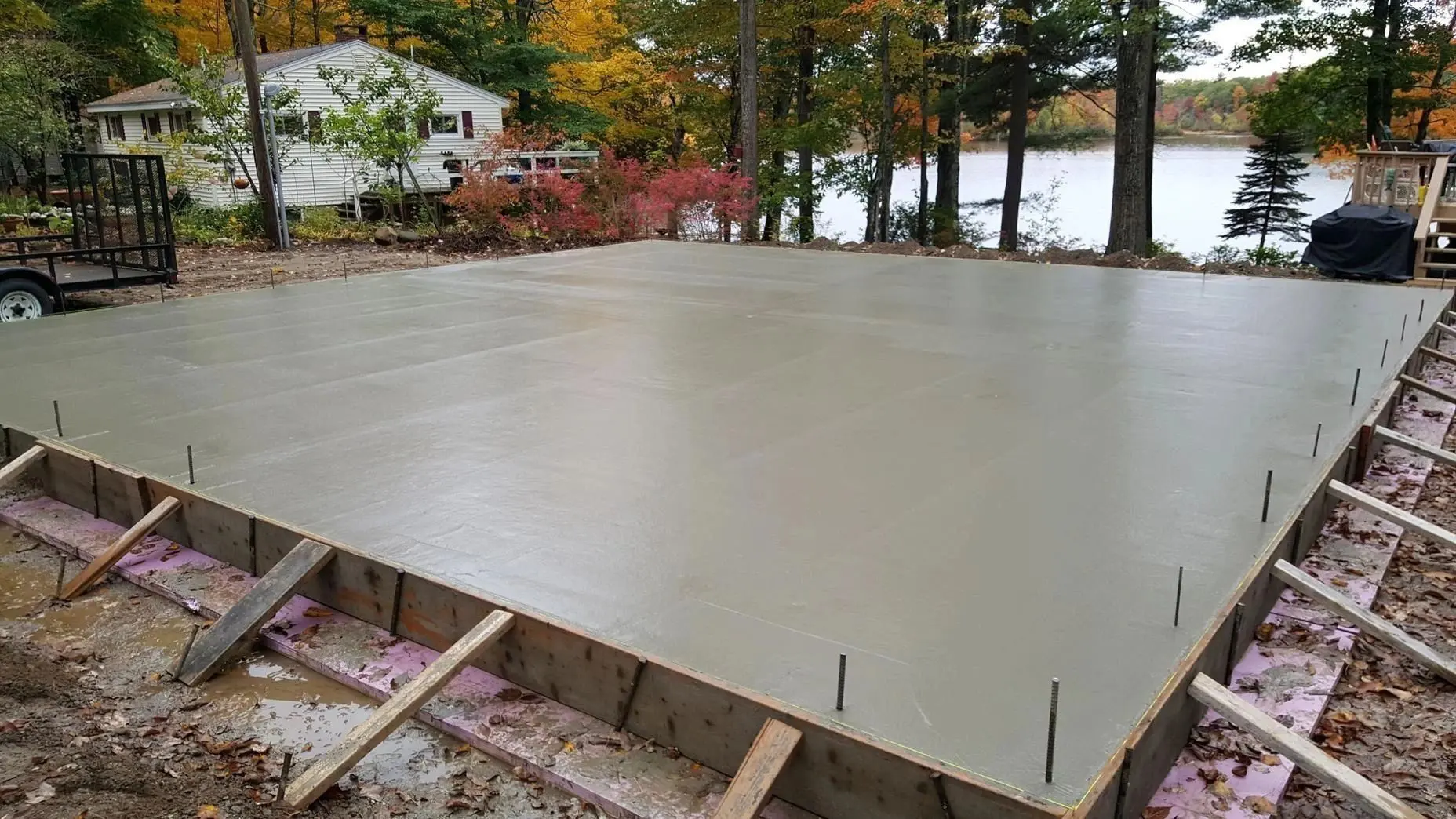 Concrete slab foundation with wooded lake backdrop.