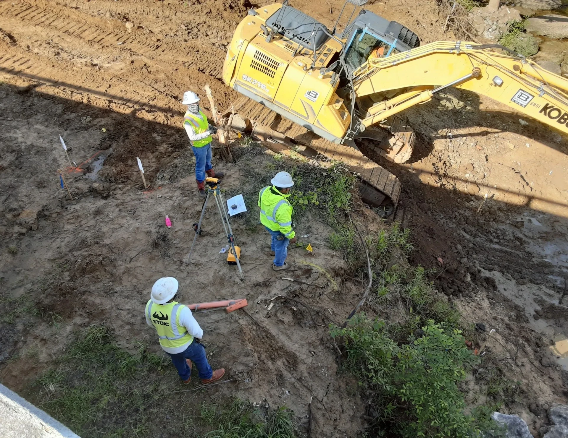 Construction workers at excavation site with excavator